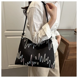 Détail du sac cabas noir avec broderie ondulée colorée et tissu à texture relief