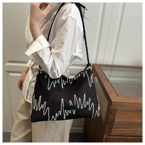 Détail d'un sac à bandoulière noir avec broderie vagues colorées et étiquette mode