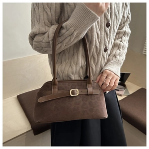 Dettaglio della borsa sottobraccio in pelle scamosciata marrone con fibbia dorata e cinturino
