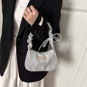Silver pleated metallic underarm bag with gold bow decoration and scrunched top handle