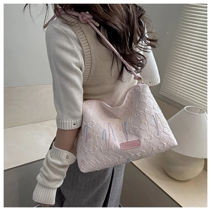 Detailed close-up of pink quilted shoulder bag with fashion label and knot strap