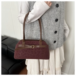 Detail of burgundy leopard print suede texture and brown leather straps on the shoulder bag