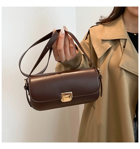 Dettaglio della borsa sottobraccio in pelle marrone vintage con fibbia dorata e modella