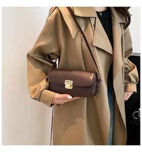 Gros plan sur le sac bandoulière en cuir marron foncé avec boucle métallique dorée