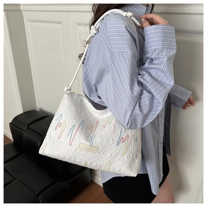 Détail du sac sous l'épaule matelassé blanc avec surpiqûres colorées et logo en cuir