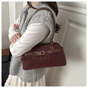 Detail of burgundy leopard print shoulder bag with brown leather straps and gold buckle