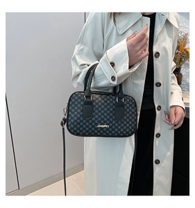 Détail du sac à main en cuir gaufré noir avec motifs géométriques et logo doré