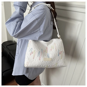 Détail d'un sac seau blanc à rayures avec broderie sur un mannequin féminin