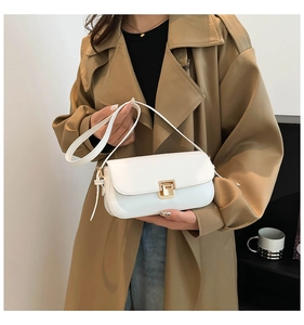 Gros plan d'un sac bandoulière en cuir verni blanc avec boucle dorée sur un mannequin