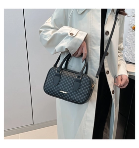 Détail du sac polochon noir à motifs géométriques avec logo de marque doré et bandoulière