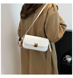 Vue arrière d'un sac bandoulière blanc avec boucle dorée porté sur un manteau kaki
