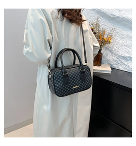 Détail d'un sac Boston noir avec motifs géométriques circulaires et accents dorés