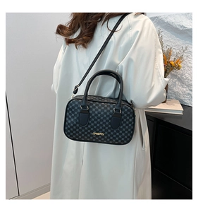 Détail du petit sac vintage avec motif monogramme porté sur un trench-coat