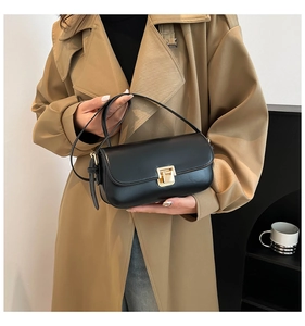 Petit sac noir chic avec fermoir doré porté par une femme en trench-coat élégant