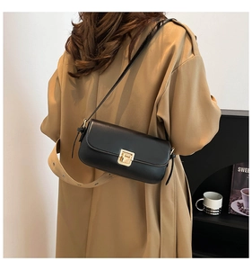 Detailansicht der minimalistischen schwarzen Ledertasche mit goldenem Verschluss am Model