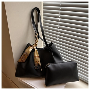 Detail of black tote bag set with white contrast stitching and decorative scarf handle