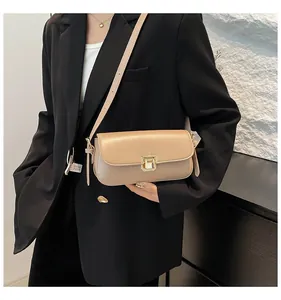 Detail of a beige minimalist shoulder bag with a gold buckle on a black suit blazer