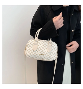 Sac Boston chic porté avec un manteau noir montrant la bandoulière et les doubles poignées