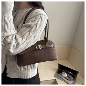 Detail shot of brown faux suede underarm bag featuring a metallic buckle and vintage texture