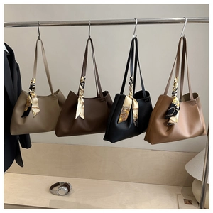 Detailed display of four textured leather tote bags with elegant silk scarf handle wraps
