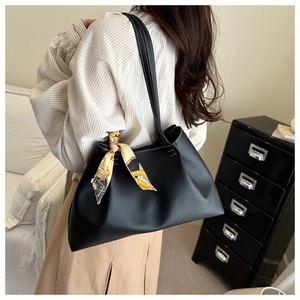 Chic black lychee leather tote bag with silk scarf detail shown on shoulder of a model