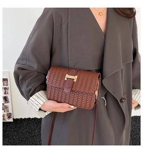 Detail of brown woven texture PU leather crossbody bag with a gold metal buckle