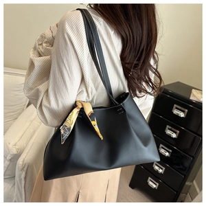 Detail of black tote bag with white contrast stitching and decorative silk scarf on strap