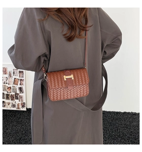 Detail shot of brown woven leather texture and gold H-buckle on crossbody bag
