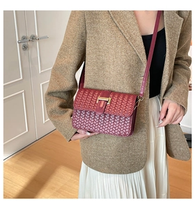 Detail view of burgundy woven texture bag with gold buckle on brown wool blazer
