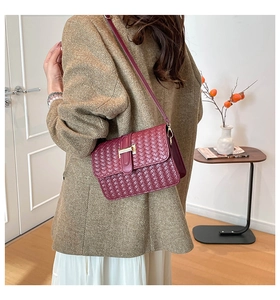 Close-up of burgundy woven leather bag featuring a gold T-bar lock and crossbody strap