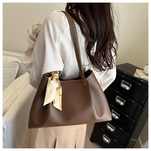 Lifestyle shot of a brown large capacity shoulder tote bag with silk scarf detail