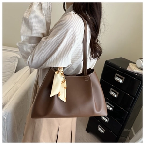 Brown leather tote bag detail with decorative silk scarf and smooth polished finish