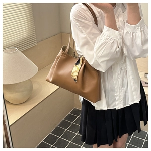Sac fourre-tout en cuir marron avec foulard en soie décoratif sur l'anse par un mannequin
