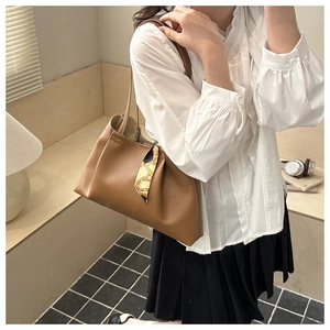 Sac fourre-tout en cuir marron avec détail de foulard en soie porté par un mannequin