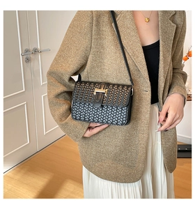 Close-up of black woven leather bag featuring a gold H buckle against a stylish suit