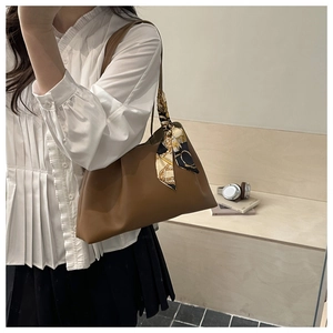Détail d'un sac à bandoulière marron en similicuir plissé avec un foulard en soie imprimé