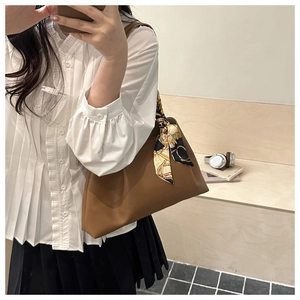 Close-up of brown matte leather tote bag featuring a decorative printed silk scarf on strap