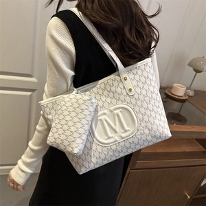Weiße Monogramm-Tragetasche mit M-Muster und großem Logo am Modell für den täglichen Gebrauch