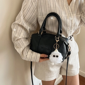 Bolso Boston de cuero negro con logo grabado y amuleto de monstruo de peluche suave