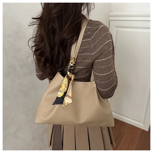 Detail of beige leather tote bag with decorative patterned silk scarf on the shoulder strap