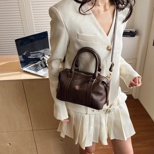 Retro dark brown Boston handbag with embossed text shown on a stylish model