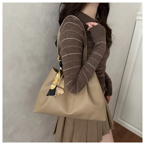 Close-up of khaki leather tote bag featuring a decorative silk scarf on the handle