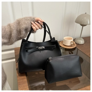 Detalle del bolso de mano negro mate con cierre de giro metálico y bolso interior a juego