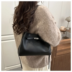 Detalle del bolso tote de cuero negro con cierre giratorio plateado y textura mate fina