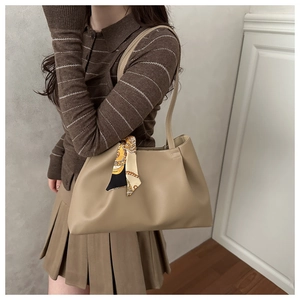 Detail of khaki oversized tote bag featuring a geometric silk scarf tied to the handle