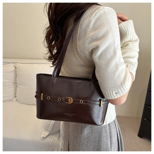Detail of dark brown glossy leather tote with gold buckle and adjustable strap