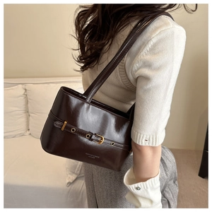 Detail view of deep brown polished leather shoulder bag with metallic buckle and text