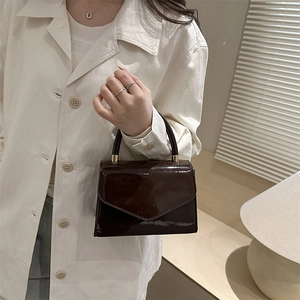 Minimalist chocolate brown patent leather crossbody bag with a metallic handle for women