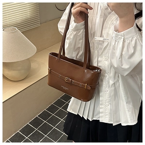 Detail of brown leather tote showing gold buckle strap and printed fashion logo