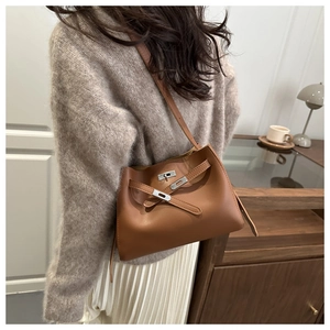 Bolso bandolera de cuero marrón con hebilla de cinturón mostrado en escena lifestyle